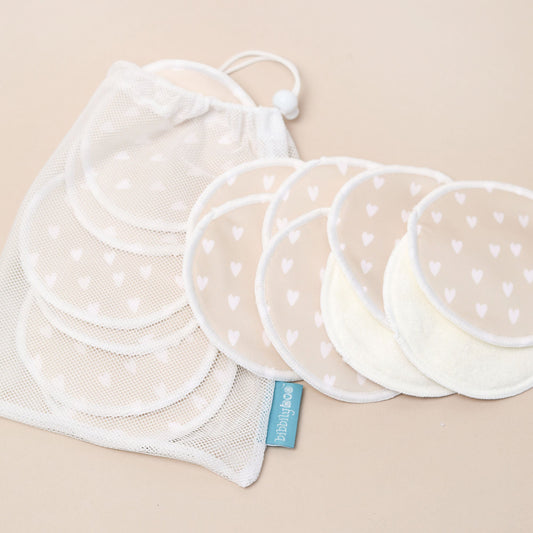 Set of white reusable breastfeeding pads with a laundry bag on a beige background