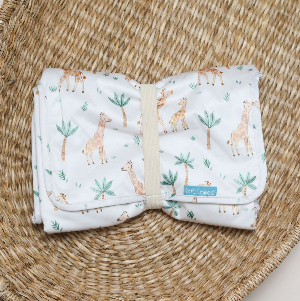 Baby changing mat with giraffe pattern on a beige background