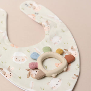 Baby bib with teether on a sage green background