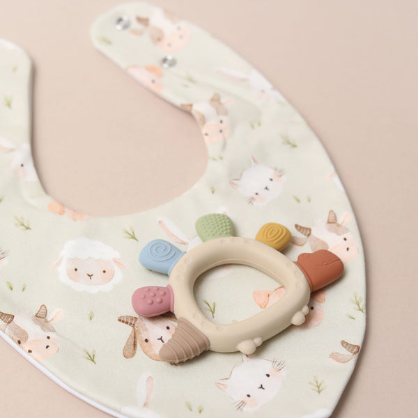 Baby bib with teether on a sage green background